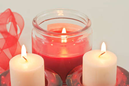 Set of three candles with flame and red ribbonの写真素材
