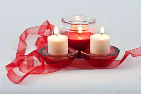 Set of three candles with flame and red ribbonの写真素材