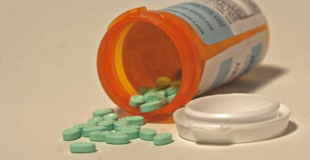 Drugs in pill form coming out of a fallen bottle.の写真素材