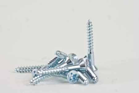 Apile of assorted screws with one screw standing on a white background.の写真素材