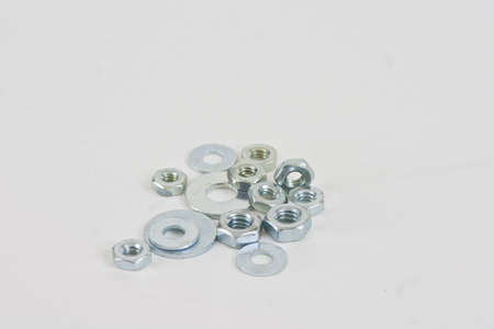 A pile of assorted nuts and washers on a white background.の写真素材