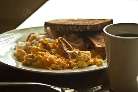 A full view of a plate of breakfast food ready to eat with coffee cup in forground.の写真素材