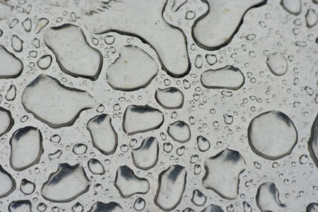 Water droplets collected on the top of a shinny silver surface.の写真素材
