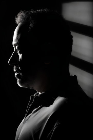Portrait of a black man in a dark room with blindsの素材