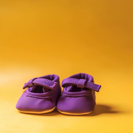 Purple baby shoes on a yellow background. Selective focus.の素材