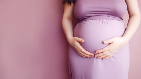 Pregnant woman touching her belly over pink background. Copy space.の素材