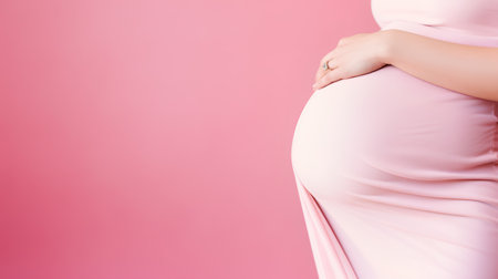 Pregnant woman in pink dress on pink background. Copy space.の素材