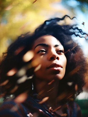 young pretty african american woman with curly hair in autumn park, lifestyle people conceptの素材