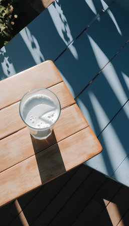 Glass of milk on a wooden table in the shade of the sunの素材