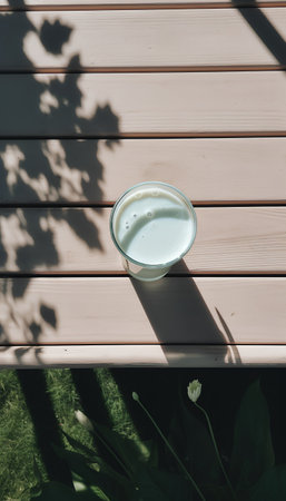Glass of milk on a wooden table in the shade of a treeの素材