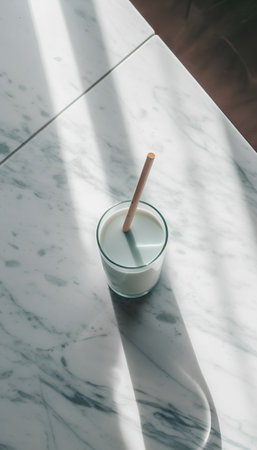 A glass of milk with a straw on a marble countertop.の素材