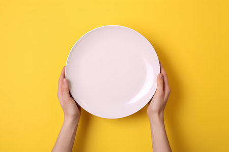 cropped view of woman holding plate on yellow background, food conceptの素材