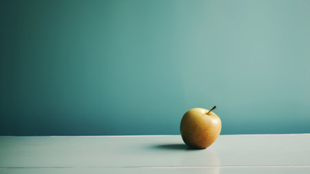 Yellow apple on a wooden table against a blue wall with copy spaceの素材