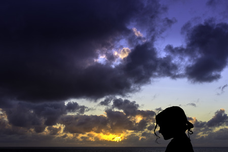 Silhouette of a young girl with sunrise over the ocean in background - Los Cocoteros, Lanzarote, Canary Islands, Spainの写真素材