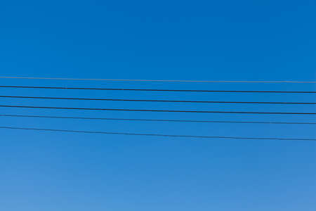 electricity cable against blue skyの写真素材
