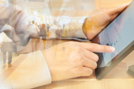 young asian businessman hand on computer tablet with twilight business skyscraper background, business communication conceptの写真素材