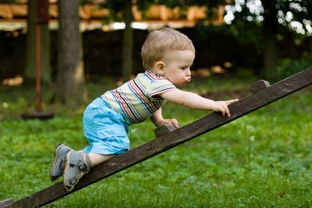 Happy young boy creeping on the ladder in the parkの写真素材