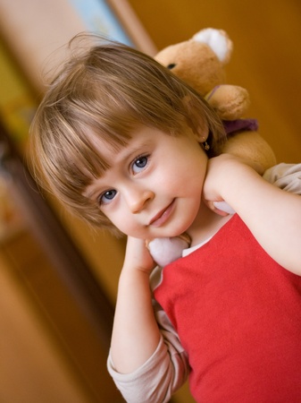Portrait of cute little girl with a teddy-bear behind her neckの写真素材