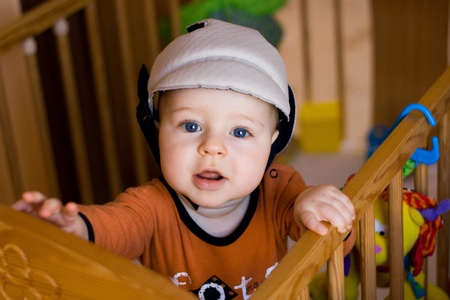 Portrait of the small happy child in a safety helmet standing in the bedの写真素材