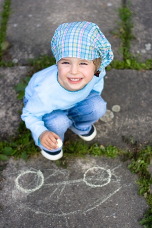 Portrait of cute little girl drawing a car on the groundの写真素材