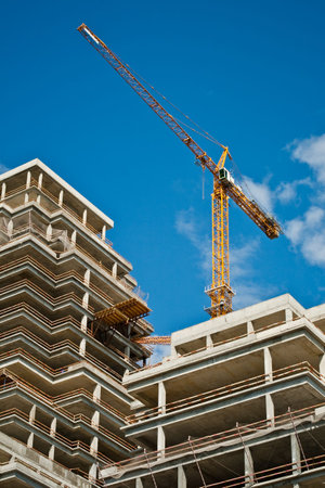 Building crane and building under construction against skyの写真素材