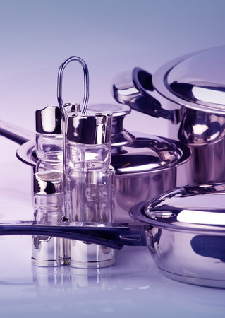Stainless steel pepperbox and saltcellar over utensil backgroundの写真素材