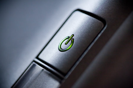 Green glowing power button. Closeup shot.