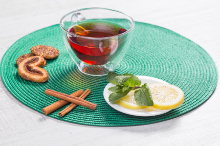 Glass cup of tea on a wooden table with sliced lemon and cinnamon.の写真素材