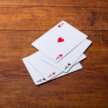 Four aces vintage poker game playing cards on a weathered wood table in an old western frontier gambling establishment saloon.の写真素材