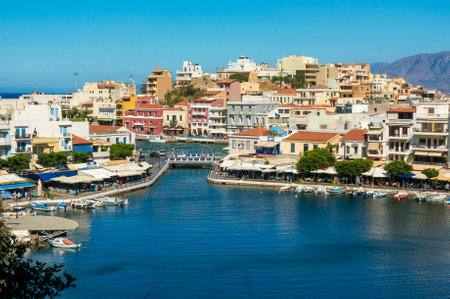 AGIOS NIKOLAOS, GREECE - JULY 20, 2014: Waterfront with outdoor greek tavern, small shops and boats in harbor of Agios Nikolaos, Crete, Greece.のeditorial素材