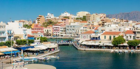 AGIOS NIKOLAOS, GREECE - JULY 20, 2014: Waterfront with outdoor greek tavern, small shops and boats in harbor of Agios Nikolaos, Crete, Greece.のeditorial素材