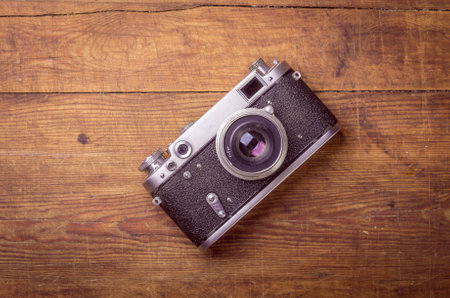 Retro camera on wood table background, vintage color tone