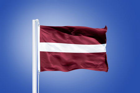 Flag of Latvia flying against a blue sky.の写真素材
