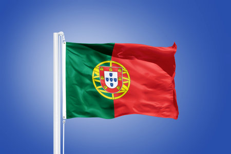 Flag of Portugal flying against a blue sky.