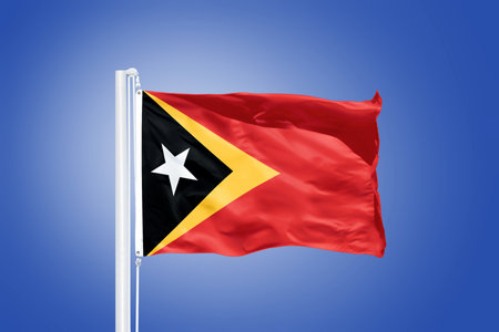 Flag of East Timor flying against a blue sky.の写真素材