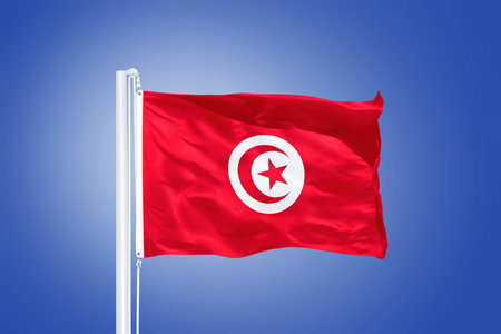 Flag of Tunisia flying against a blue sky.の写真素材