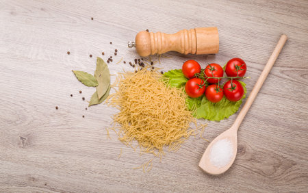 Pasta, tomatoes and pepper on a wooden background.の写真素材