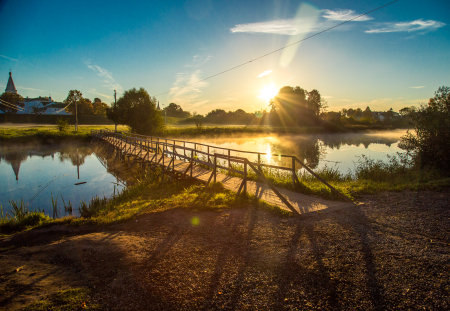 wooden bridge through river in morning sunlight.の写真素材