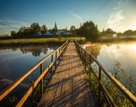 wooden bridge through river in morning sunlight.の写真素材