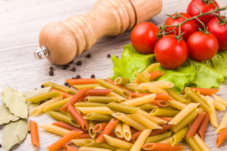 Pasta, tomatoes and pepper on a wooden background.の写真素材