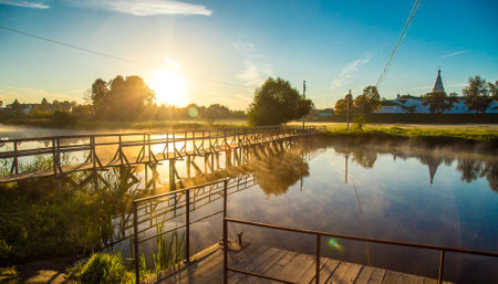 wooden bridge through river in morning sunlight.の写真素材