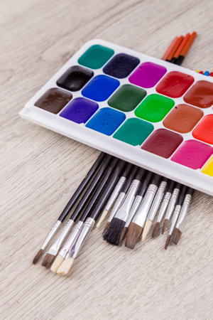 Watercolor paints with set of paint brushes on wooden backgroundの写真素材