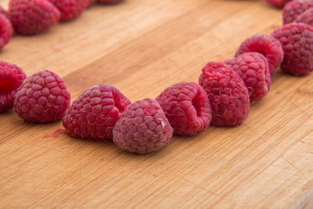 Ripe sweet raspberries on wood table close-up.