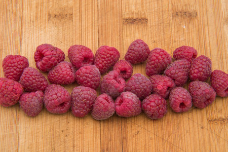 Ripe sweet raspberries on wood table close-up.
