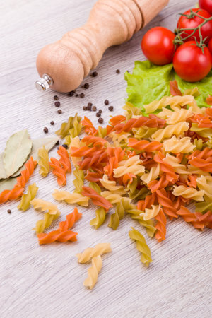 Pasta, tomatoes and pepper on a wooden background.の写真素材