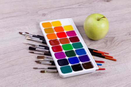 Watercolor paints with set of paint brushes on wooden background.の写真素材