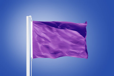 Purple flag flying in a stiff breeze against clear blue sky.の写真素材