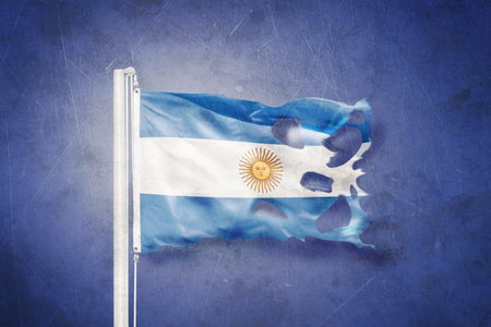 Torn flag of Argentina flying against grunge backgroundの写真素材