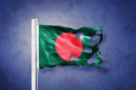 Torn flag of Bangladesh flying against grunge background