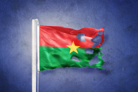 Torn flag of Burkina Faso flying against grunge backgroundの写真素材